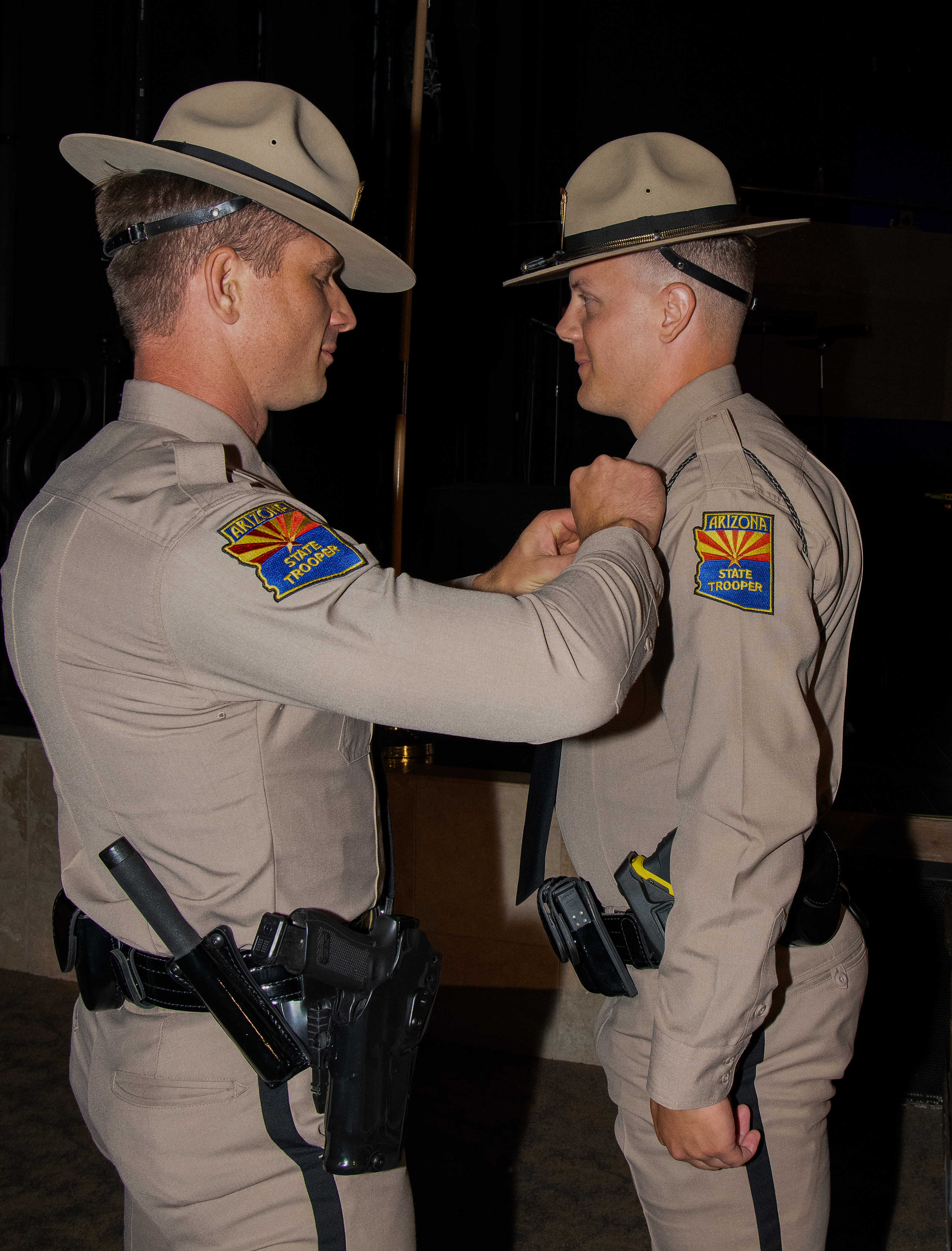 A trooper has his badge pinned by an academy class staff member