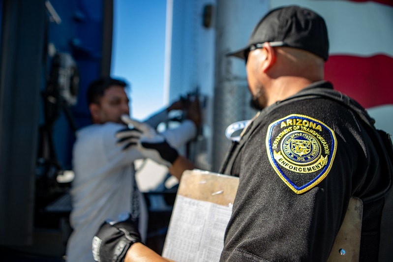 An ADOT ECD inspector is shown speaking with a commercial vehicle driver beside a truck